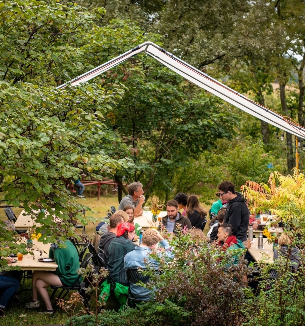 Land Institute Prairie Festival speakers and other guests enjoy lunch under a tent on the lawn of Wes Jackson's residence.