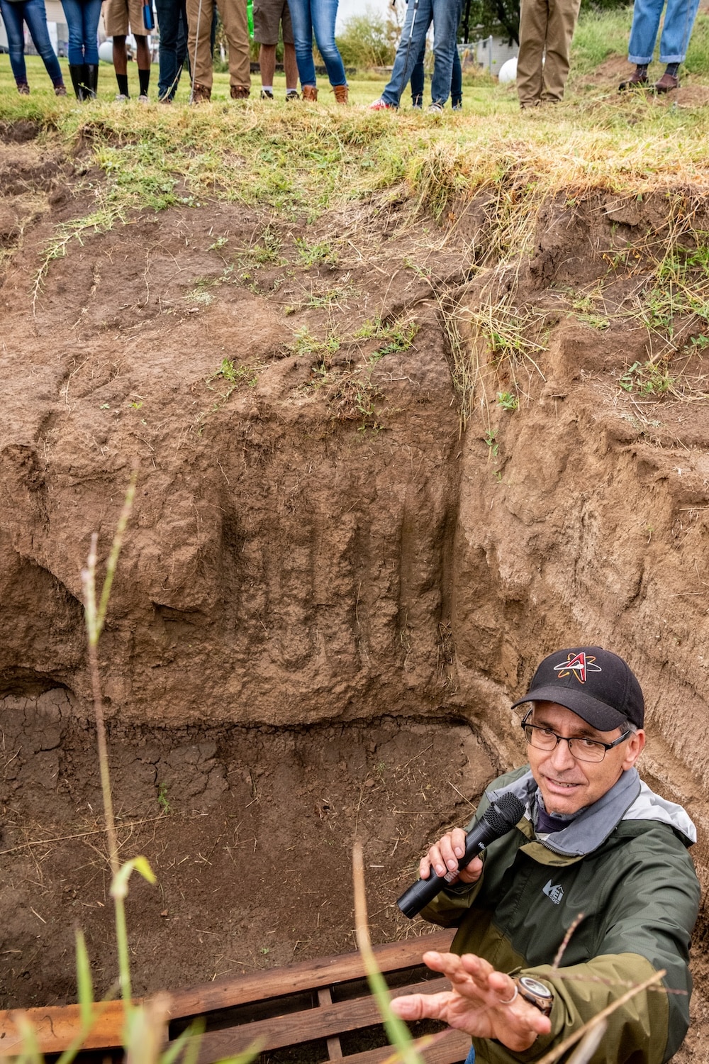 Working from a pit dug to expose plant roots, Tim Crews, The Land Institute's director of research, shows a plot tour group the depth of Kernza roots.